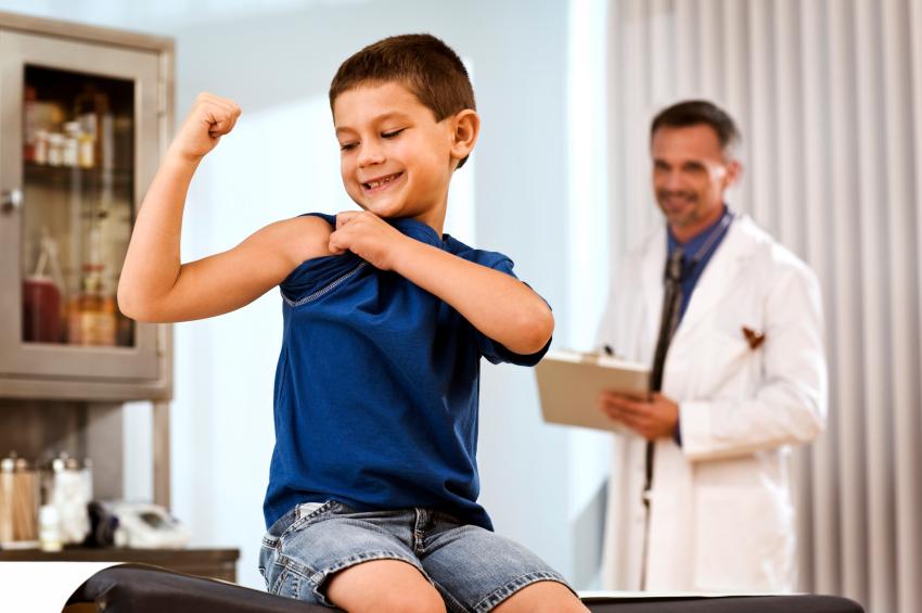 Image of boy flexing arm at doctors appointment